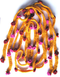 Rätstickade gula smala halsdukar med glest instickade moucher i rosa eller rost.
