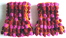 Rätstickade gula pulsvärmare med moucher i rosa, rost och rött